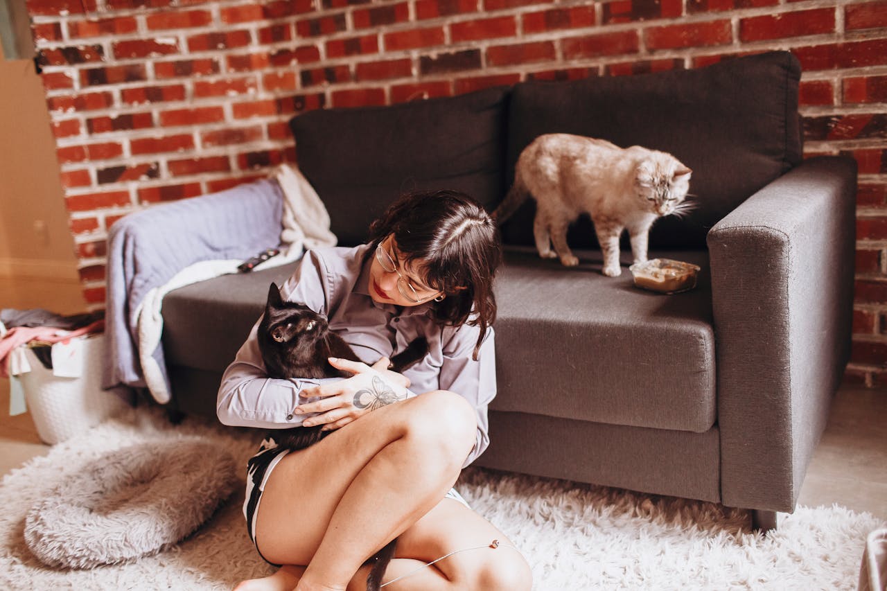 A woman enjoys a quiet moment with her cats in a comfortable living room.